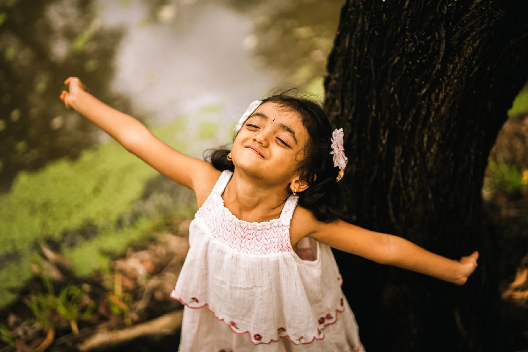 Happy little girl with her arms stretched wide outdoors