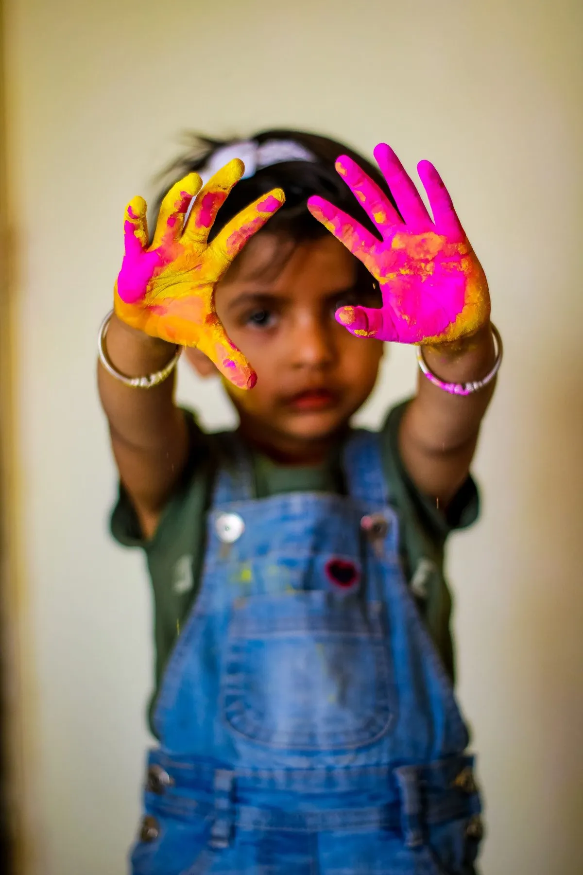 Little girl showing hands covered in bright paint