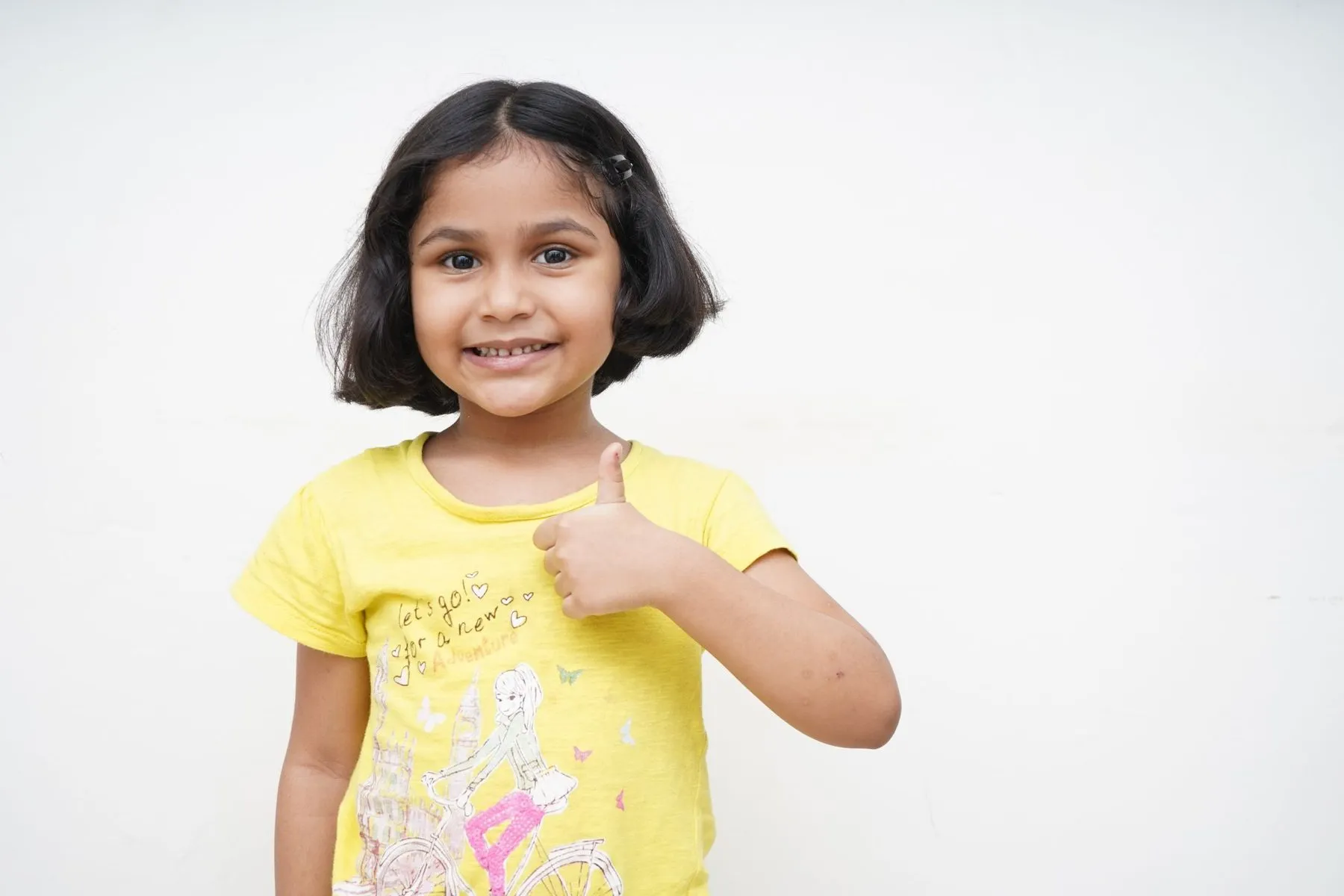 Smiling little girl giving a thumbs up